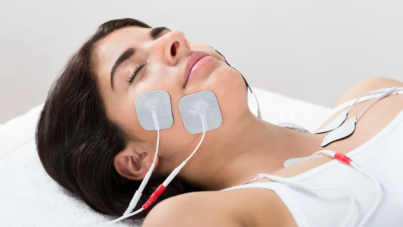 EMS pads applied to the cheek and jawline for facial muscle stimulation